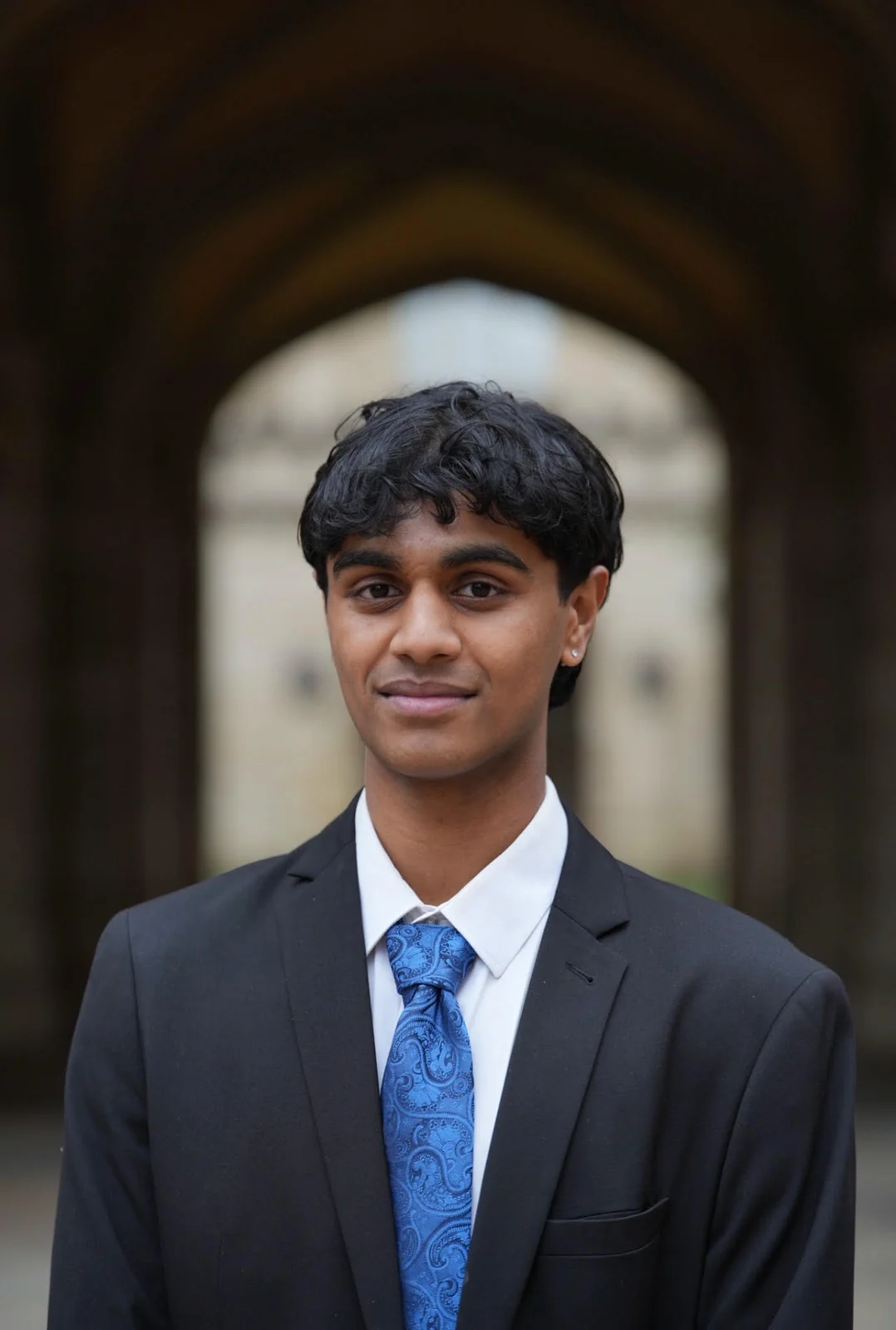 Portrait of Sahil Gawade in a suit beneath a stone archway